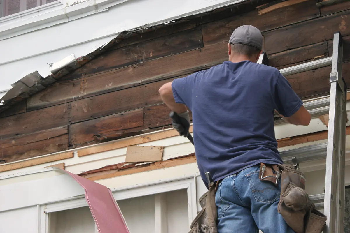 Contractor removing storm damaged siding to check the wall underneath