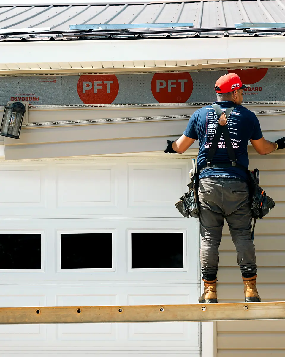 American Home crew member installing new siding above a garage