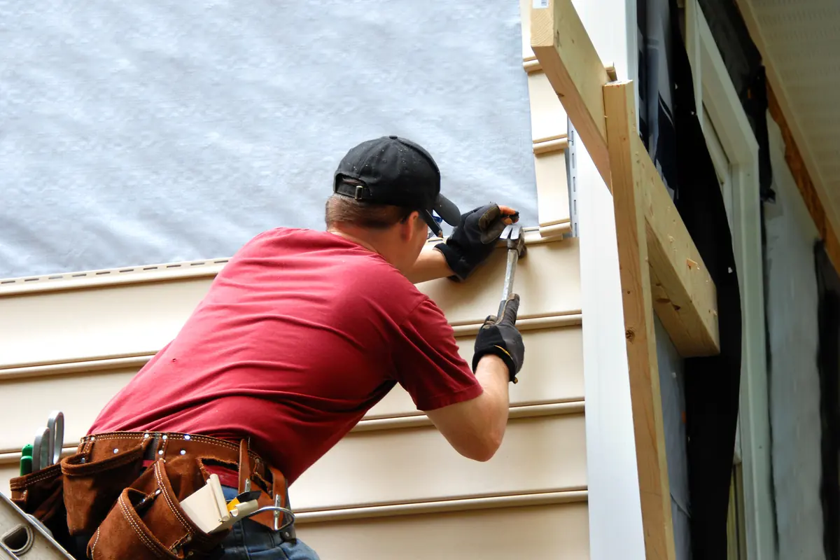 Siding installer fastening a new siding panel